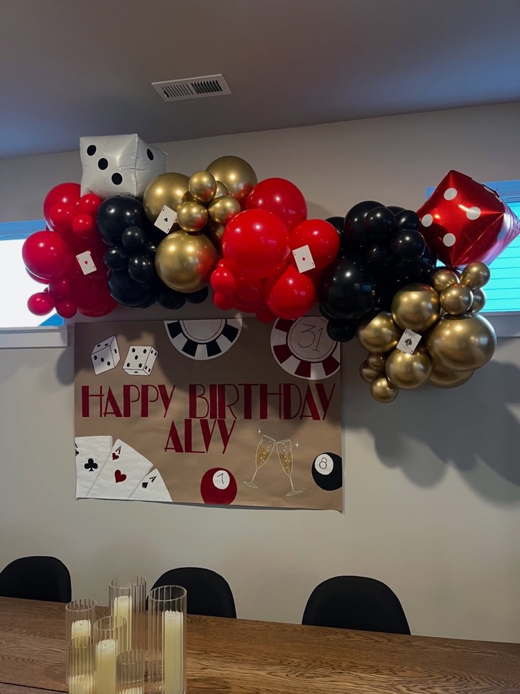 Casino themed birthday balloon arch in red, black and gold