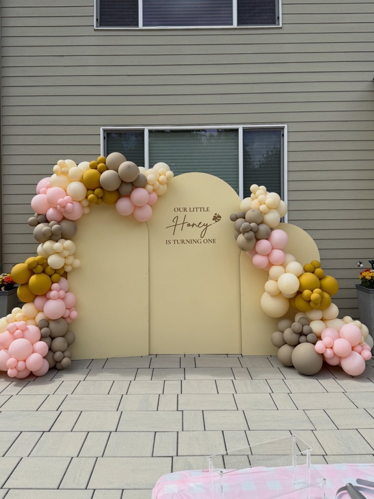Honey themed birthday display with three panels and a balloon arch
