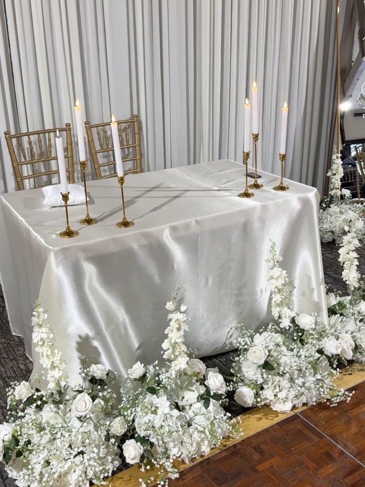 Sweetheart table surrounded by white floral bouquets