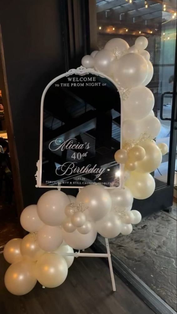 Custom welcome mirror on an easel with a pearl white balloon garland
